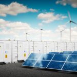 Battery storage units are stationed among solar panels and wind turbines.