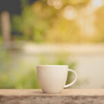 Coffee in a white cup on a bench outdoors