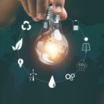 A hand holds a lightbulb surrounded by sustainability icons