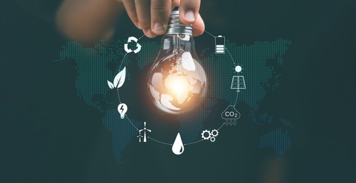A hand holds a lightbulb surrounded by sustainability icons