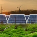 Ground-mounted solar arrays with wind turbines in the background